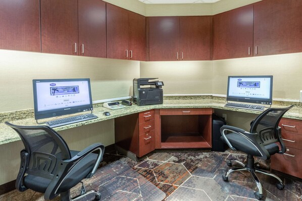 A conference room with two desks, each equipped with a computer, keyboard, and printer.