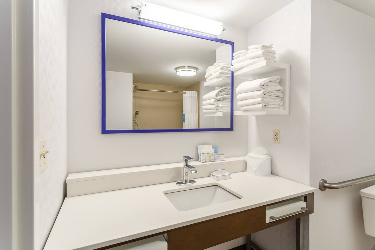 A bathroom with a white sink, a mirror with a blue frame, a towel rack, and a toilet.