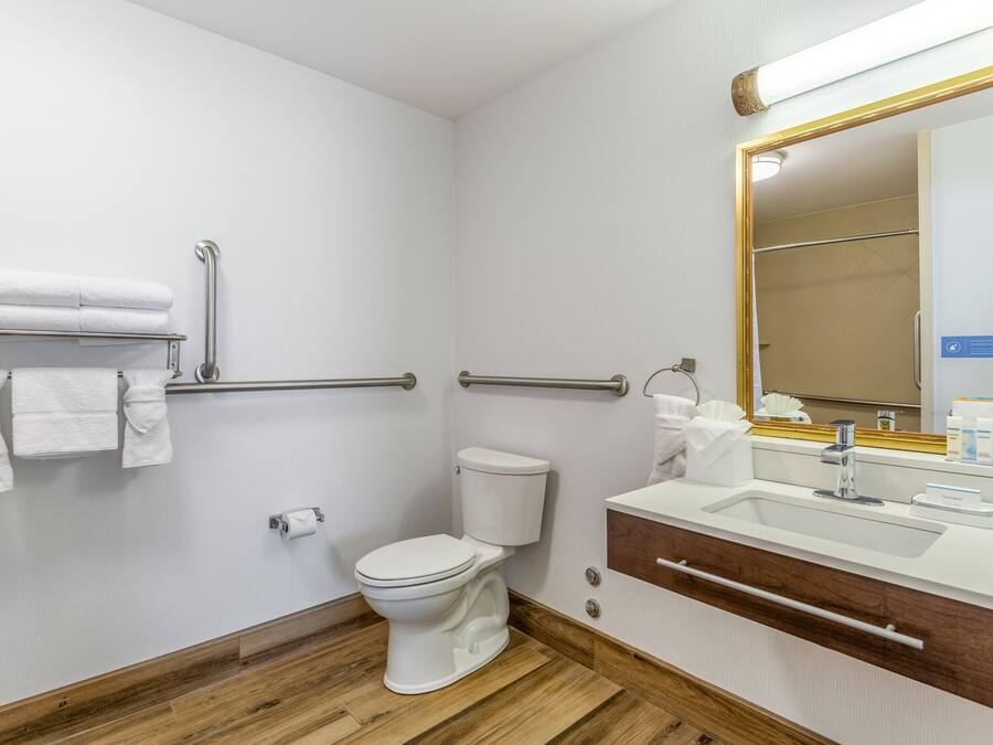 A modern bathroom with a white toilet, a sink with a mirror, and a towel rack.