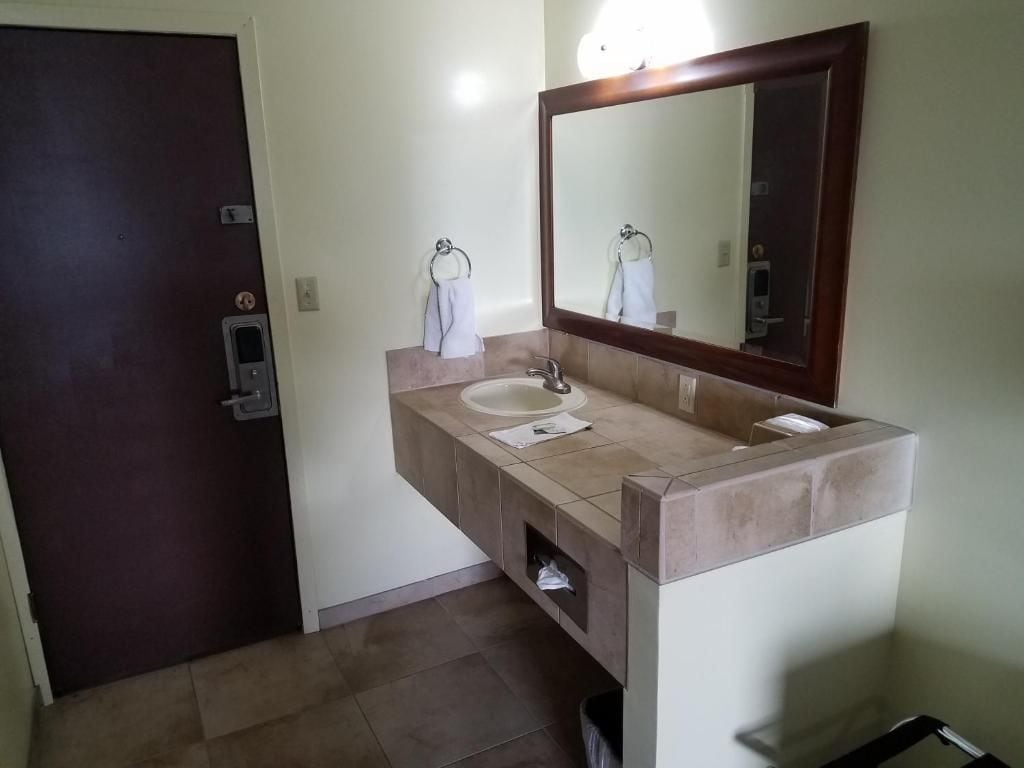 A bathroom with a sink, mirror, towel rack, and a door.
