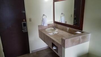A bathroom with a sink, mirror, towel rack, and a door.