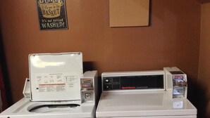 Two stacked front-loading washing machines in a laundry room with a sign on the wall. - Western Inn South (Kearney)