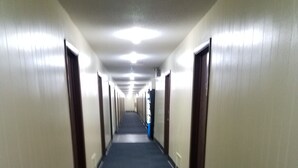 A long, narrow hallway with carpeted floors and doors on both sides. - Western Inn South (Kearney)