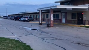 A motel with a row of parked cars and a clear sky. - Western Inn South (Kearney)