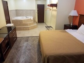 Habitación de hotel con cama, baño con bañera, escritorio y perchero.