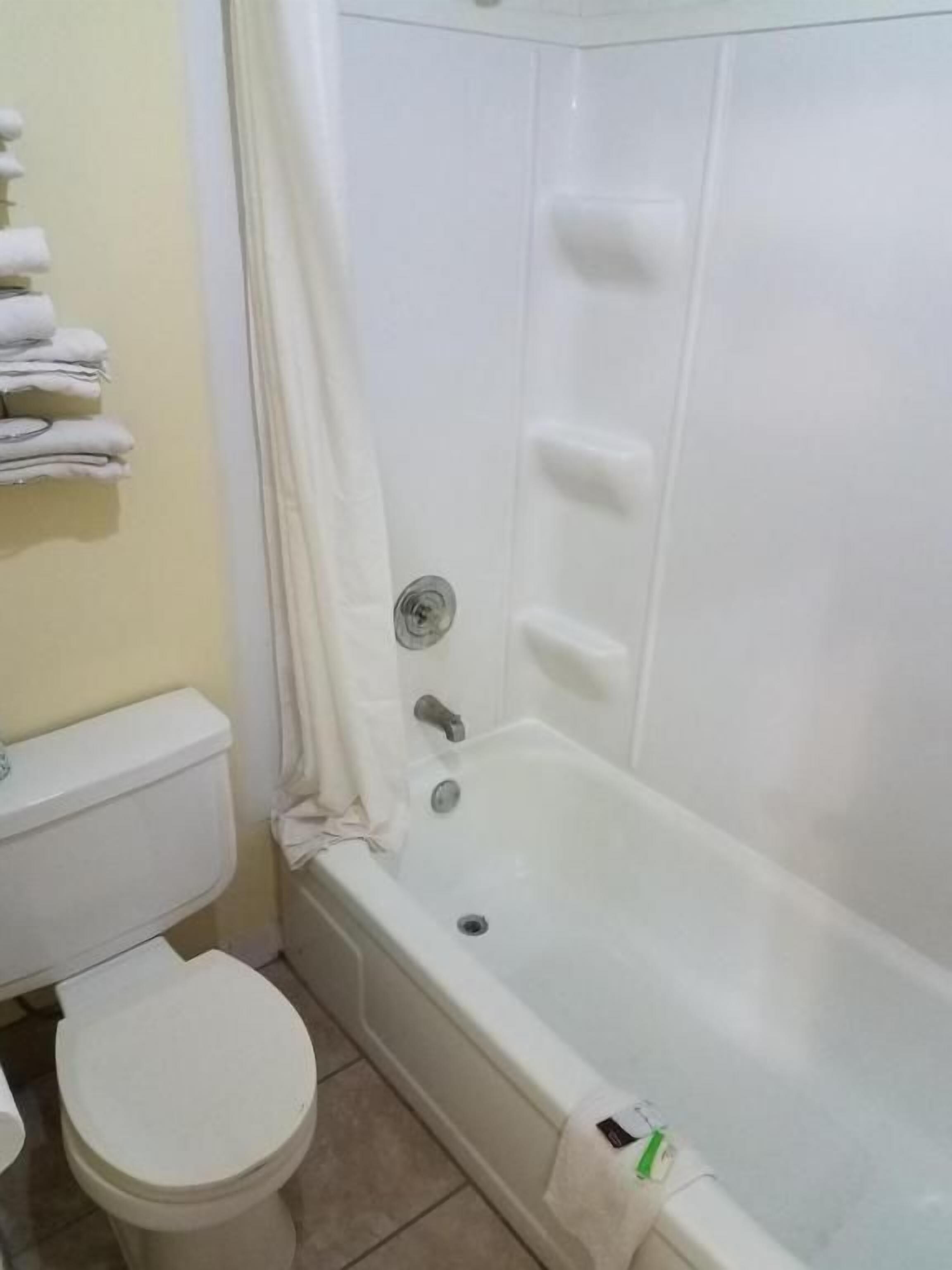 A bathroom with a white bathtub, toilet, and a towel rack with folded towels.