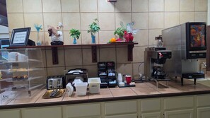 A breakfast counter with a toaster, coffee machine, and a juice dispenser. - Western Inn South (Kearney)
