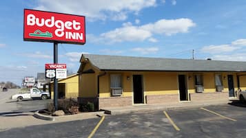 A Budget Inn with a vacant sign, a parking lot, and a church sign in the background.