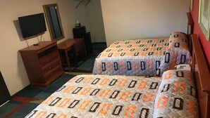 Ett hotellrum med två sängar, ett skrivbord, en TV och en spegel.