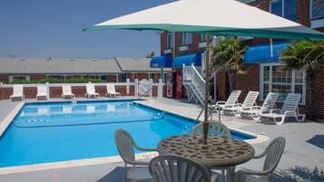 Una piscina al aire libre de temporada, sillones reclinables de piscina