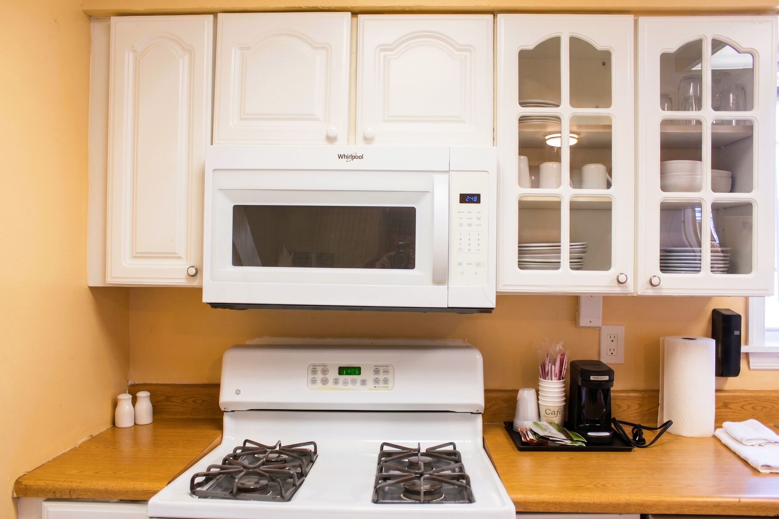A kitchen with a white microwave, stove, and cabinets.