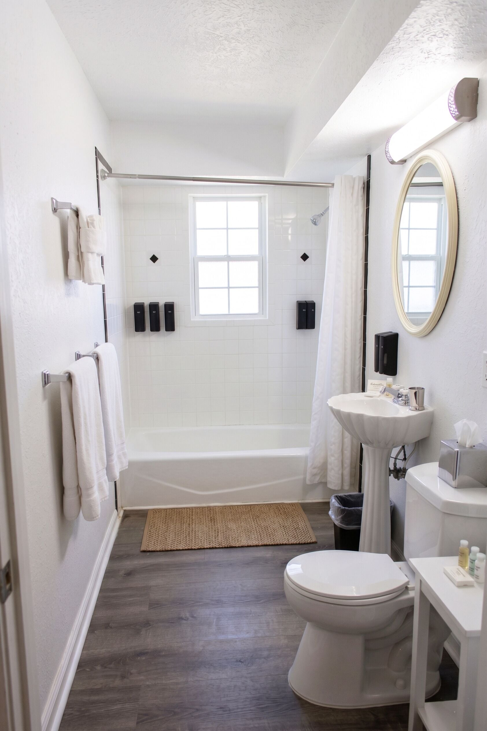 A bathroom with a bathtub, toilet, sink, and a large mirror.