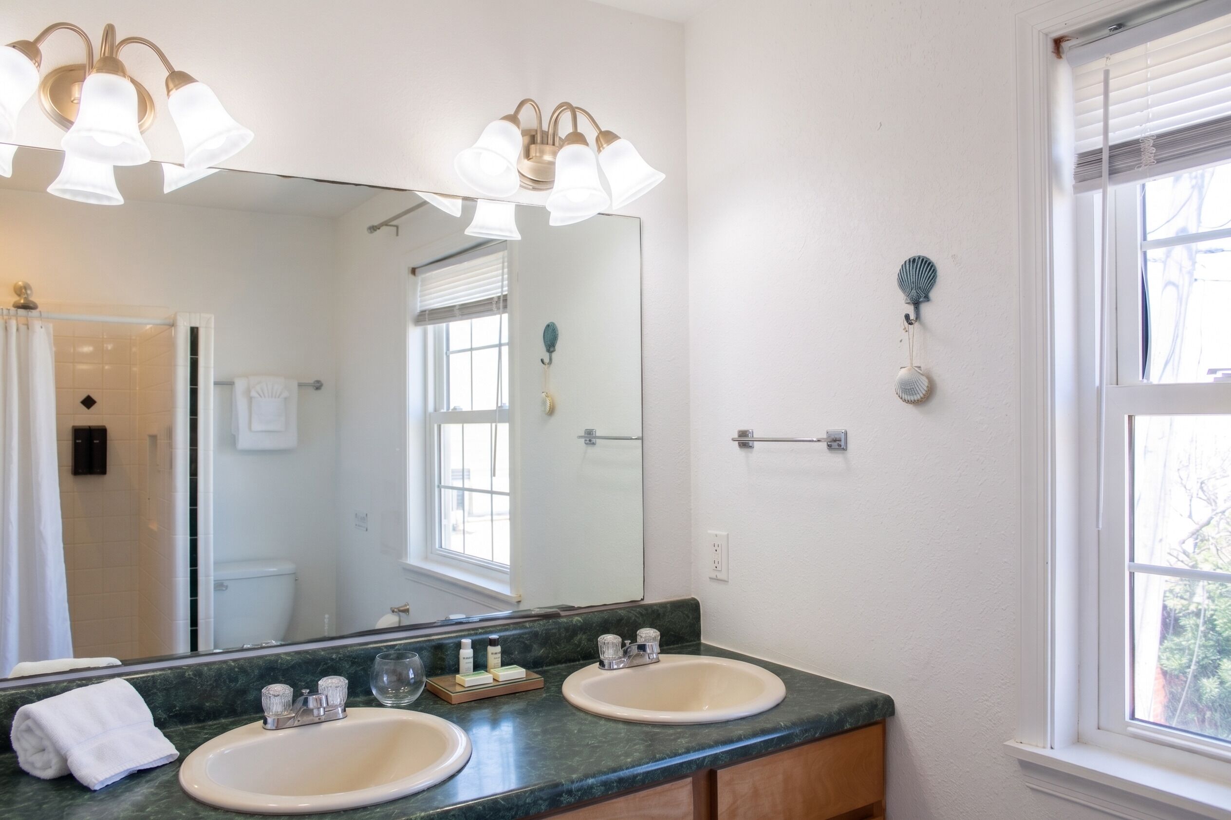 A bathroom with a large mirror, two sinks, and a shower.