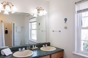 A bathroom with a large mirror, two sinks, and a shower.