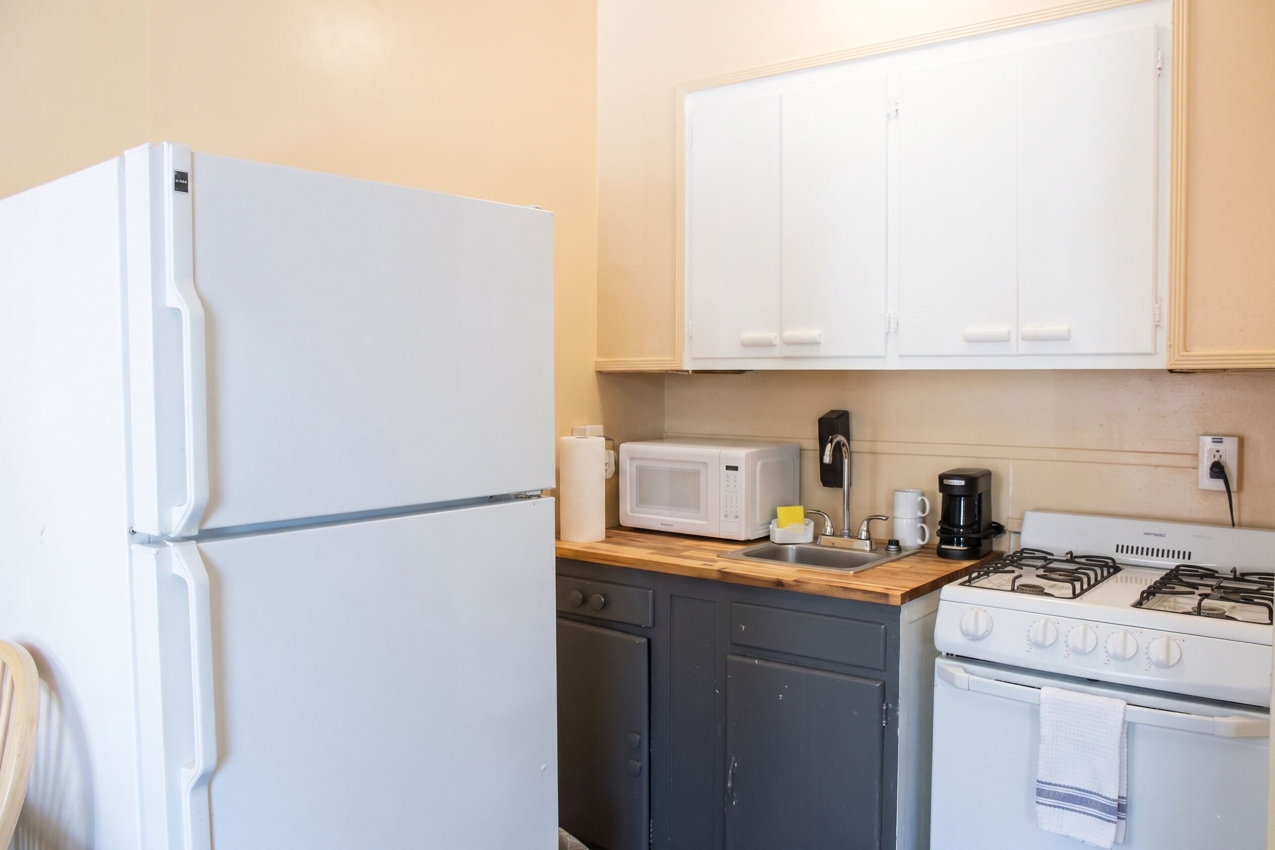 A kitchen with a white refrigerator, microwave, stove, and cabinets.
