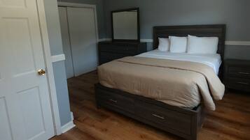 A bedroom with a bed, a dresser, a mirror, and a door.