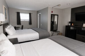 A hotel room with two beds, a TV, a desk with a chair, a mirror, and a window with curtains.