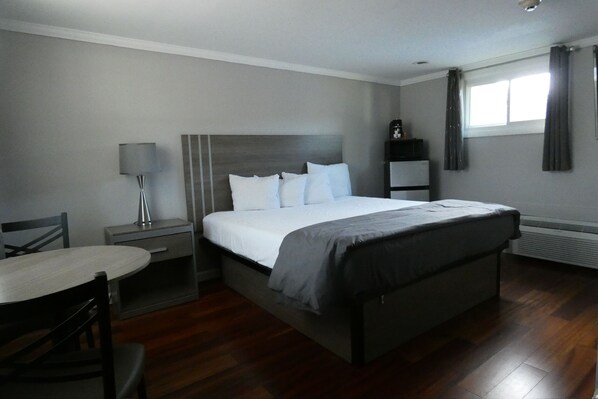 A bedroom with a bed, bedside table, lamp, and a small table with chairs.