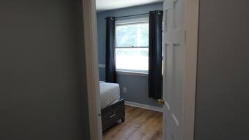 Un dormitorio con una cama, una ventana con cortinas y una puerta.