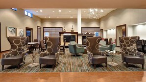 A spacious lobby with a central seating area featuring modern armchairs and a round table, a fireplace, and a television. - Residence Inn by Marriott Stillwater (Stillwater)
