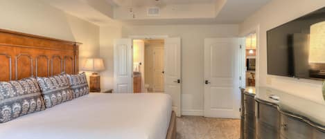 A bedroom with a bed, a ceiling fan, a dresser, and a television.