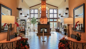 A spacious lobby with a large fireplace, high ceilings, and large windows.