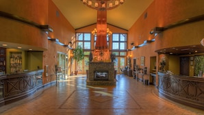A spacious lobby with a central fireplace, large windows, and a chandelier.