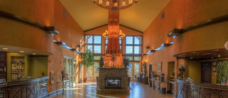 A spacious lobby with a central fireplace, large windows, and a chandelier.