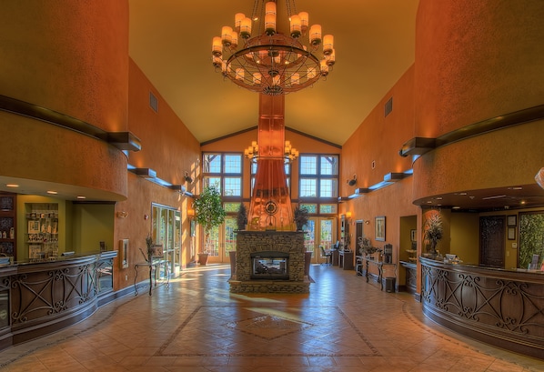 A spacious lobby with a central fireplace, large windows, and a chandelier.