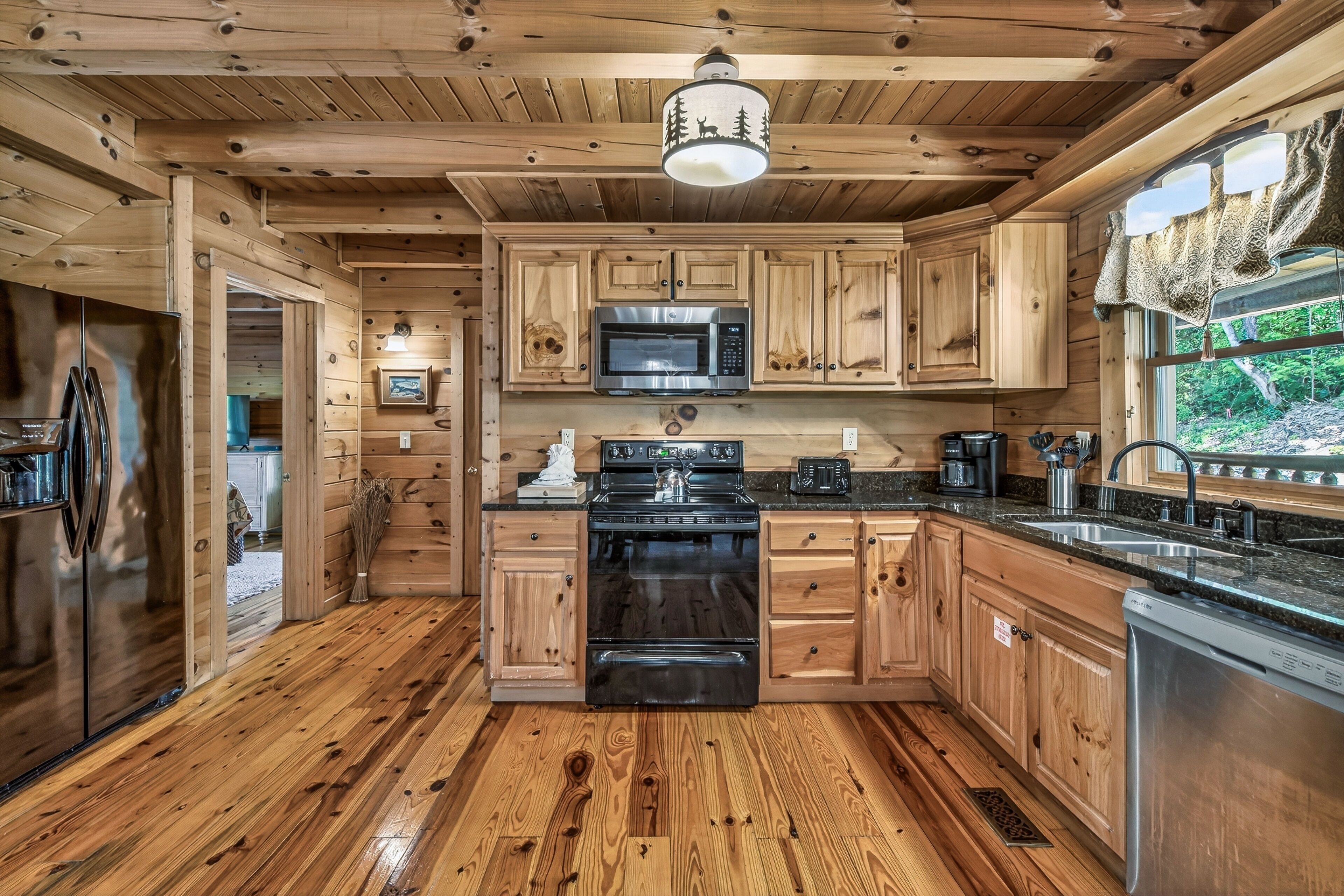 L’intérieur d’un chalet en bois comprend une cuisine équipée d’une cuisinière, d’un four à micro-ondes et d’un évier.