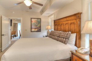 A spacious bedroom with a large bed, wooden headboard, and a ceiling fan.