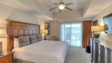 A hotel room with a large bed, a ceiling fan, a dresser, and a window with curtains.