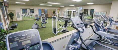 Un gimnasio con cintas de correr, elípticas y equipo de pesas.