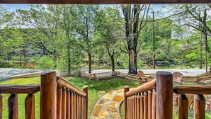A wooden fence leading to a stone pathway, surrounded by lush greenery and trees.