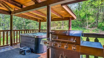 Une terrasse extérieure équipée d’un barbecue, d’un jacuzzi et d’une rambarde en bois.