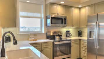 A modern kitchen with stainless steel appliances, a large window, and light-colored cabinetry.