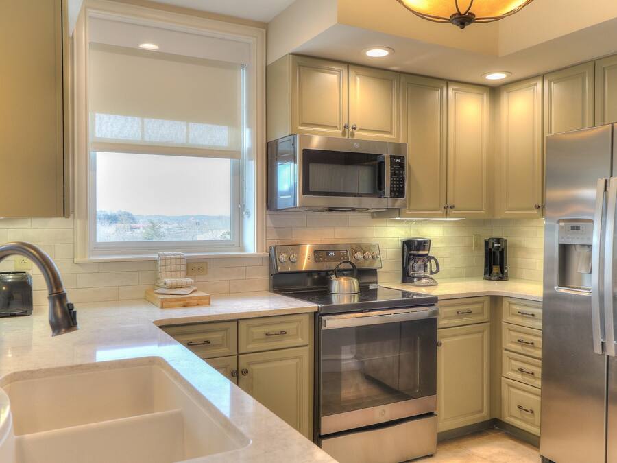 A modern kitchen with stainless steel appliances, a large window, and light-colored cabinetry.