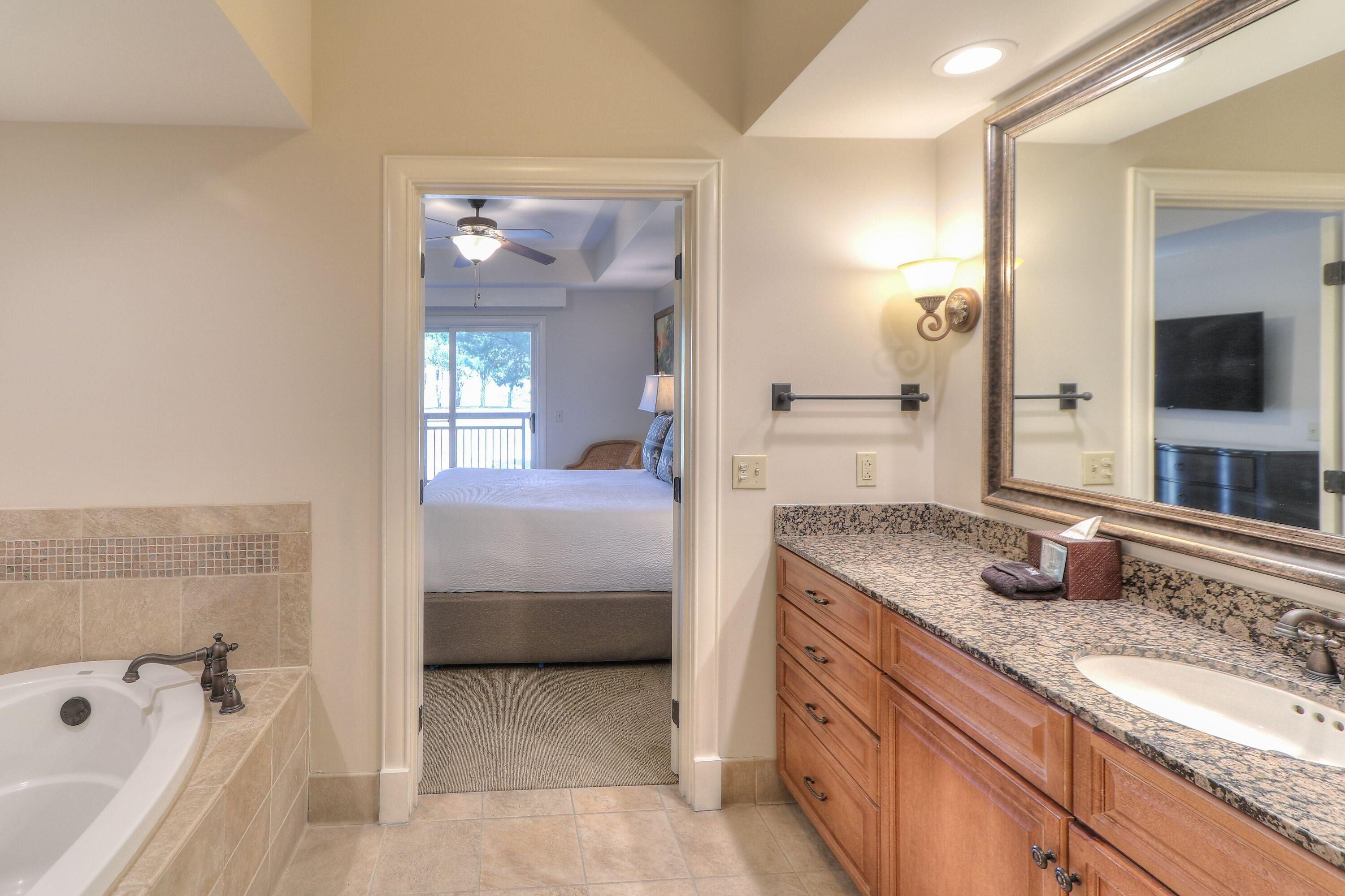 A bathroom with a bathtub, vanity with a sink, and a large mirror.