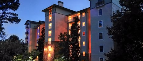 A multi-story hotel with a central courtyard, balconies, and a parking area.