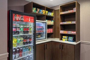 A beverage refrigerator stocked with various drinks and a snack shelf with assorted snacks. - Garner Hotel Lawton Fort Sill Area by IHG (Lawton)