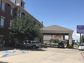 A hotel with a clear sign indicating a 14' clearance height. There are parking spaces marked with a wheelchair accessibility symbol. - Garner Hotel Lawton Fort Sill Area by IHG (Lawton)