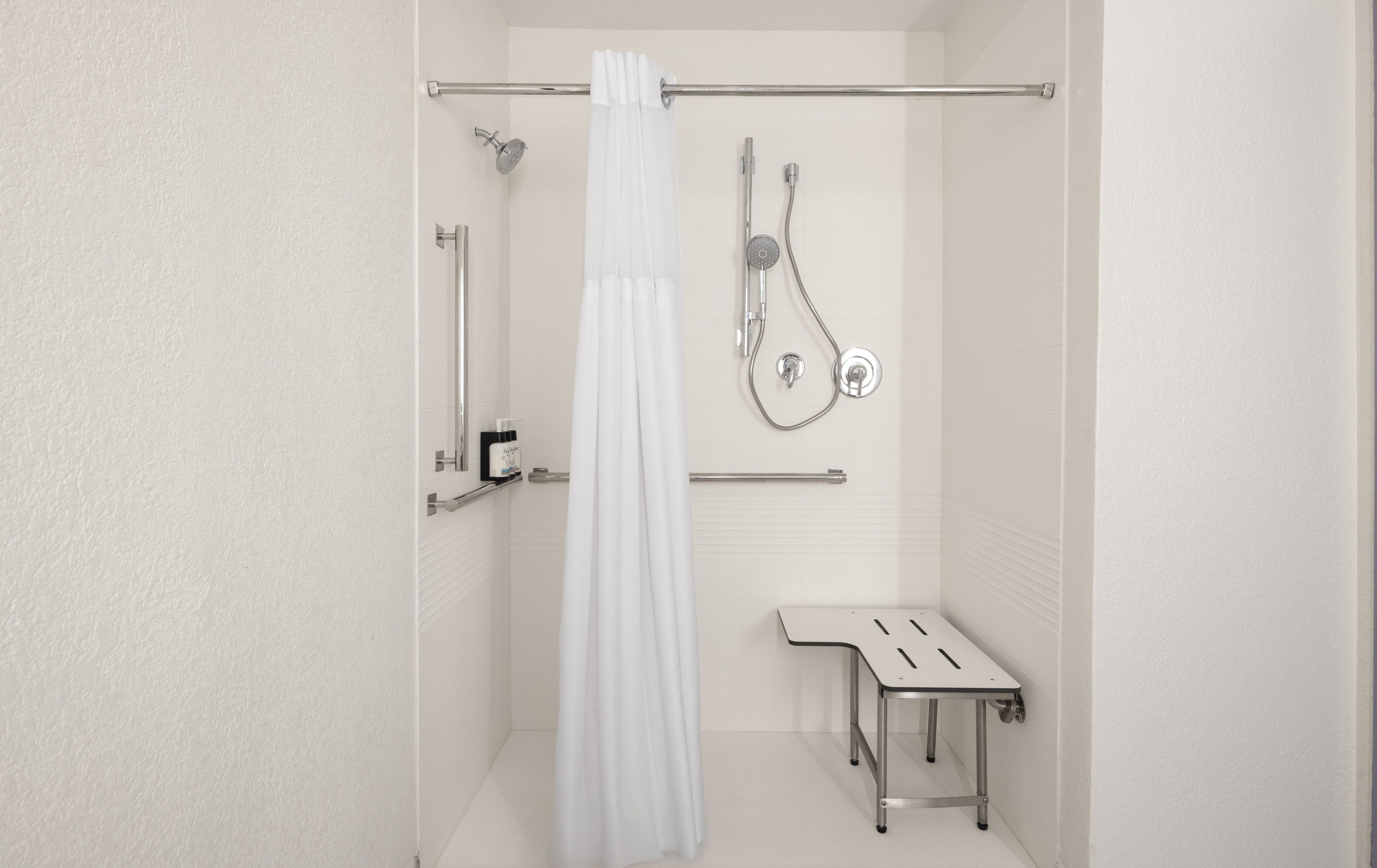A bathroom with a shower, a toilet, and a bench.