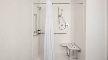 A bathroom with a shower, a toilet, and a bench.