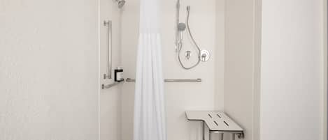 A bathroom with a shower, a toilet, and a bench.