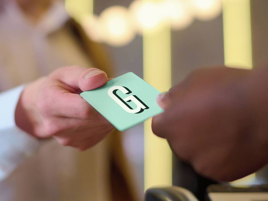 Une main tenant une carte sur laquelle est inscrite la lettre « G ».