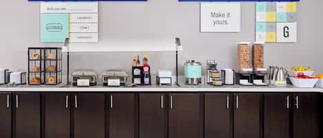A buffet setup with labeled food stations including eggs, bacon, and whole milk.