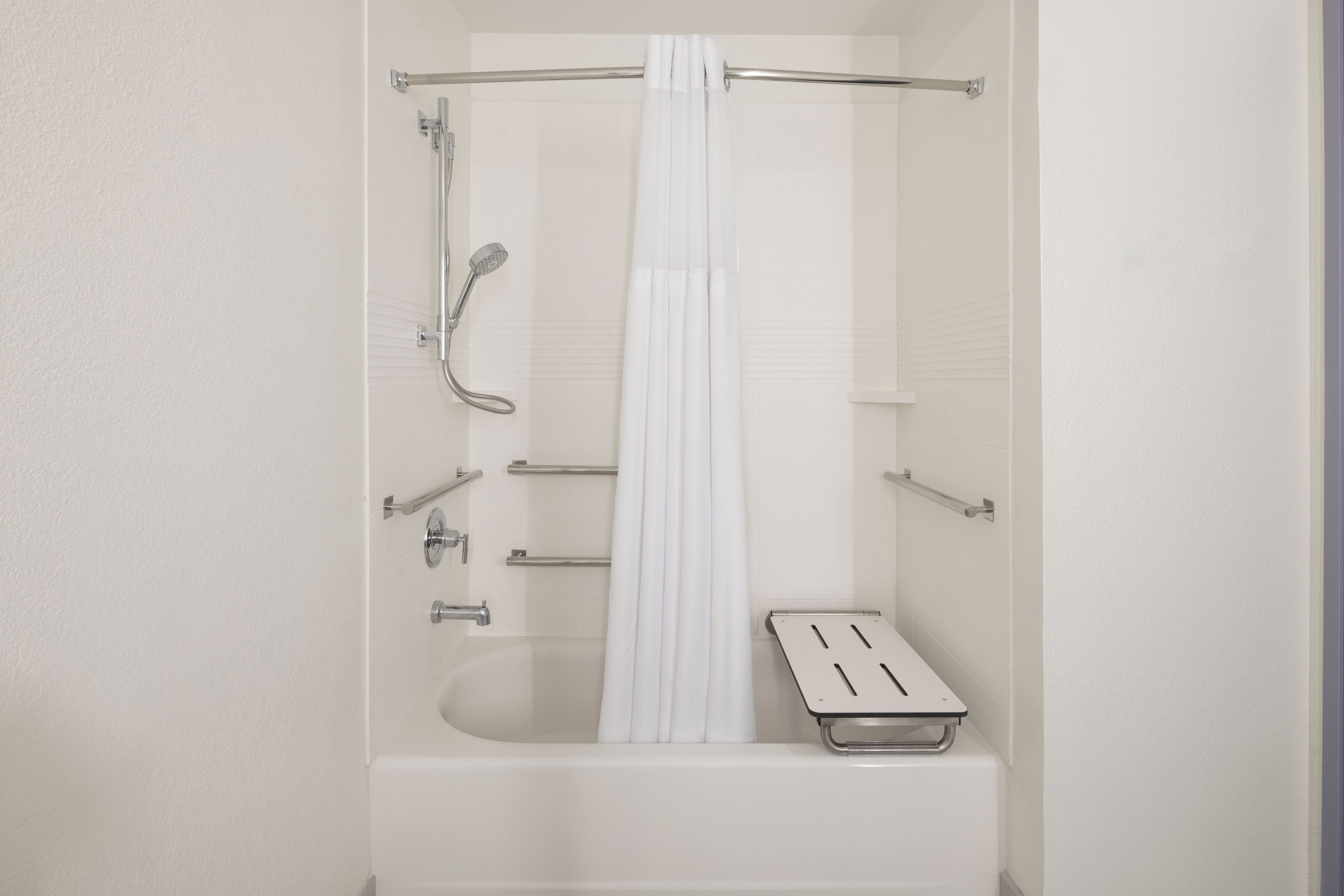 A modern bathroom with a bathtub, a showerhead, a towel rack, and a shower curtain.
