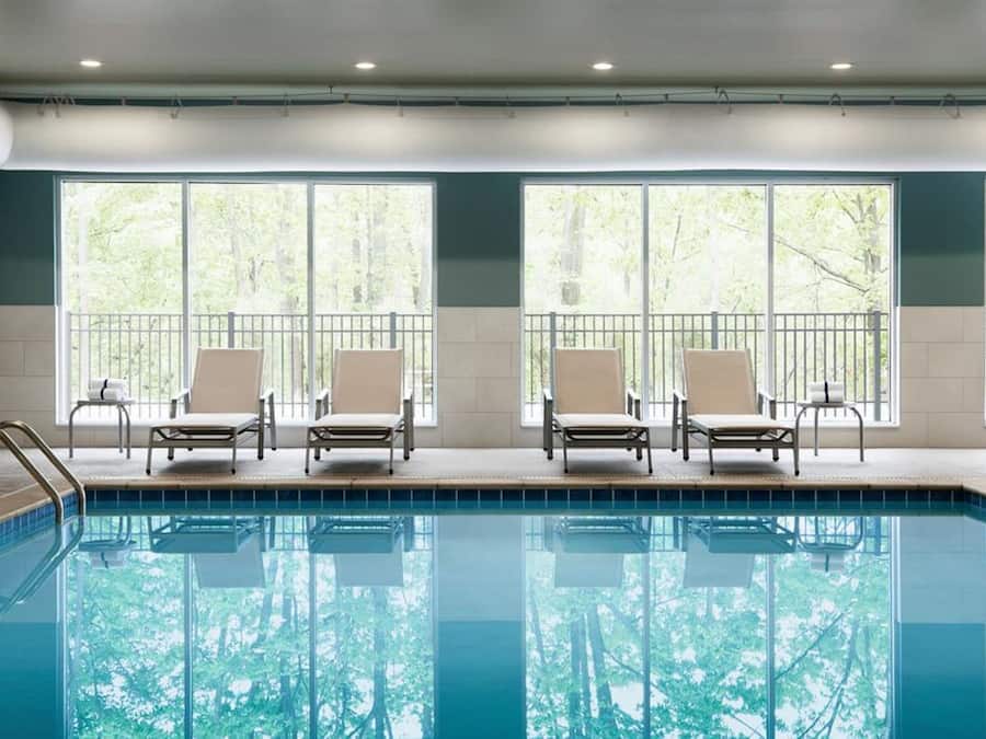 Une piscine avec quatre chaises longues et un escalier en métal.