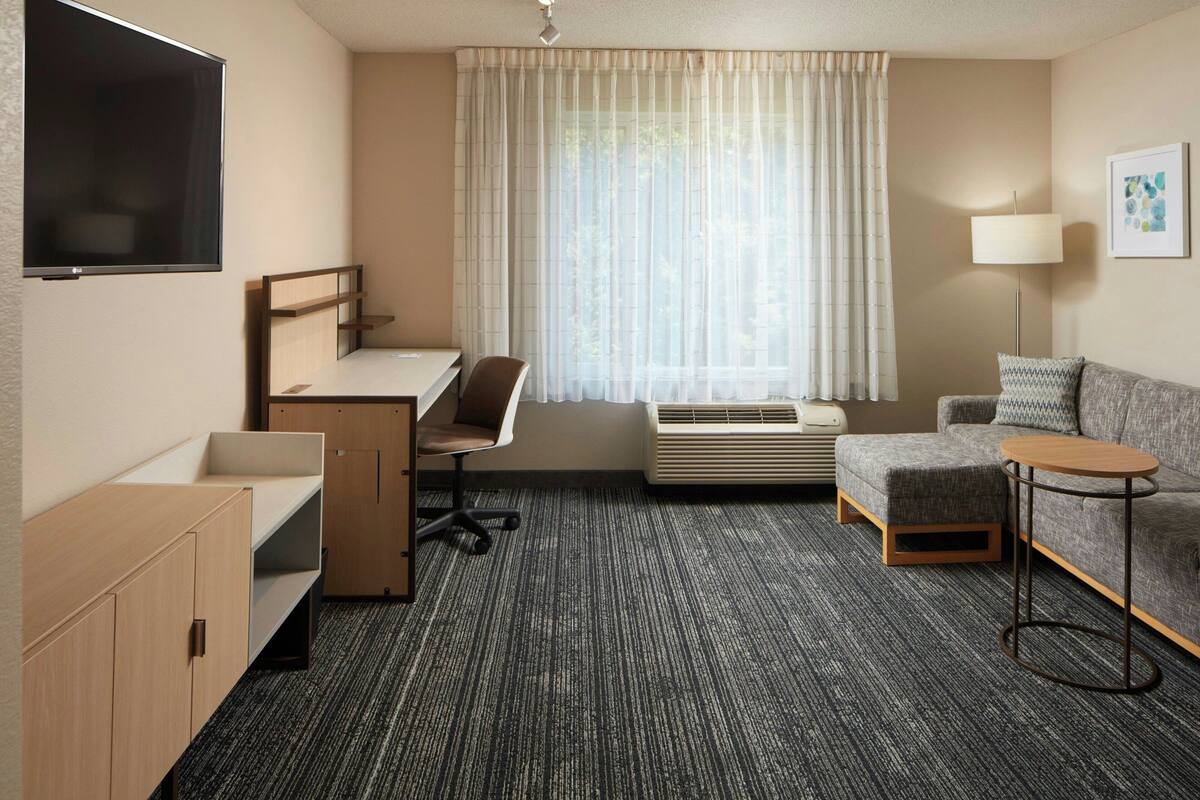Een hotelkamer met een bureau, stoel, bank en een kleine tafel.