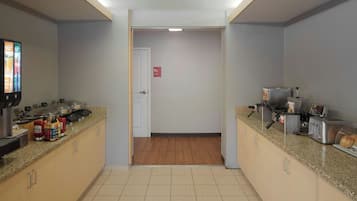 A kitchen area with granite countertops, a coffee machine, a toaster, and a bread display.